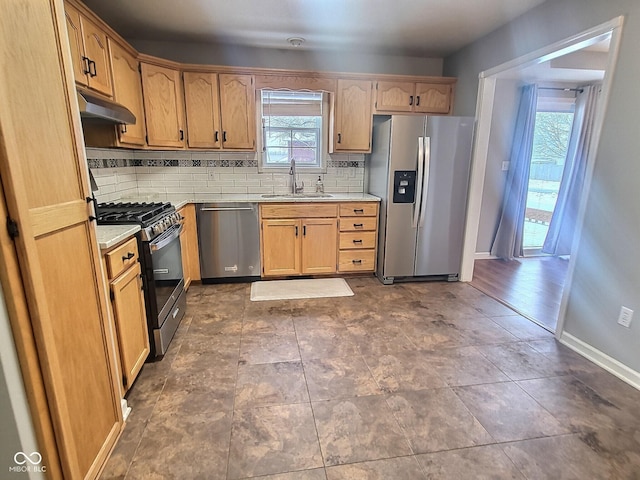 kitchen with appliances with stainless steel finishes, sink, backsplash, and dark tile patterned flooring