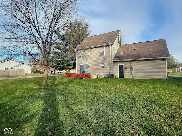 back of property featuring cooling unit and a lawn