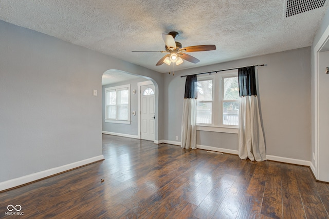 spare room with a textured ceiling, ceiling fan, a healthy amount of sunlight, and dark hardwood / wood-style floors