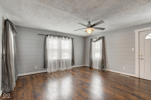 spare room with ceiling fan, a healthy amount of sunlight, and dark wood-type flooring