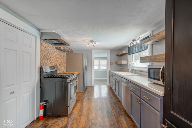 kitchen with wall chimney range hood, backsplash, dark hardwood / wood-style flooring, appliances with stainless steel finishes, and sink