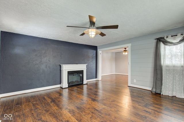 unfurnished living room featuring a textured ceiling, ceiling fan, and dark wood-type flooring