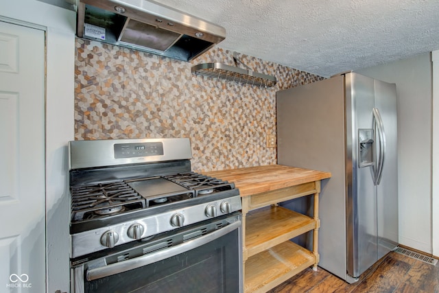 kitchen with a textured ceiling, dark hardwood / wood-style floors, stainless steel appliances, exhaust hood, and tasteful backsplash