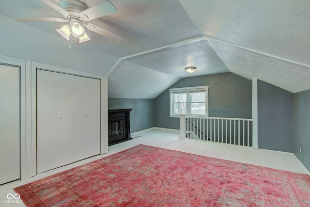 additional living space featuring a textured ceiling, ceiling fan, and vaulted ceiling