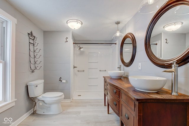 bathroom featuring wood-type flooring, walk in shower, vanity, and toilet