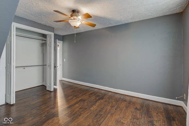 unfurnished bedroom with dark wood-type flooring, a textured ceiling, ceiling fan, and a closet