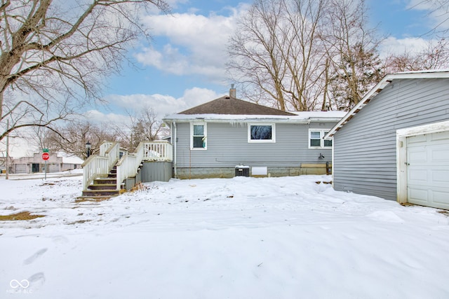 snow covered property featuring a garage and cooling unit