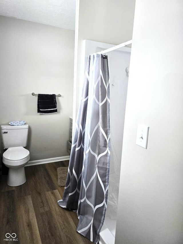 bathroom with curtained shower, toilet, and wood-type flooring