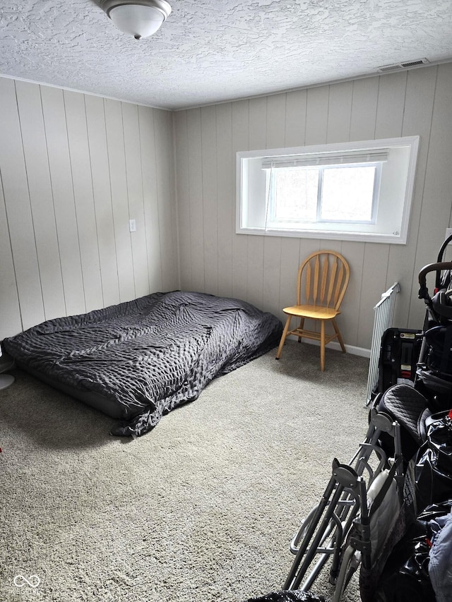 carpeted bedroom featuring wood walls and a textured ceiling