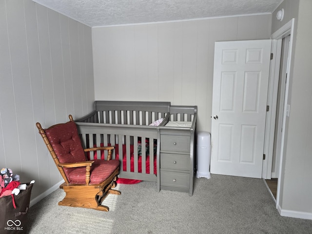 bedroom with a crib, a textured ceiling, and carpet floors