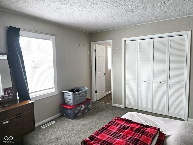 carpeted bedroom with a textured ceiling and a closet