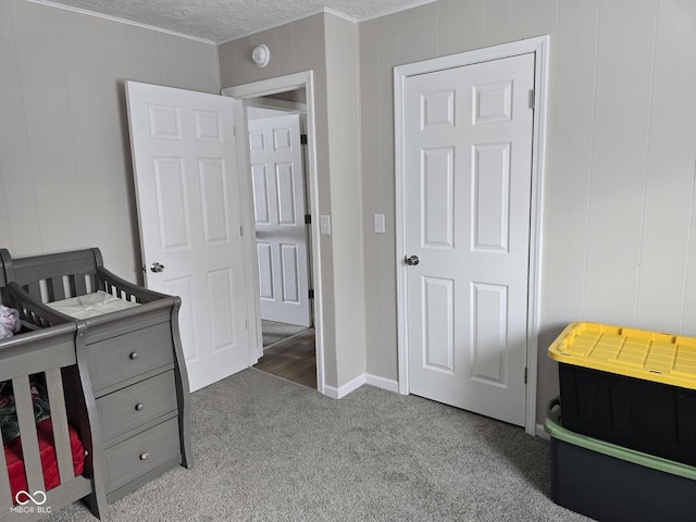 carpeted bedroom with a textured ceiling and a nursery area