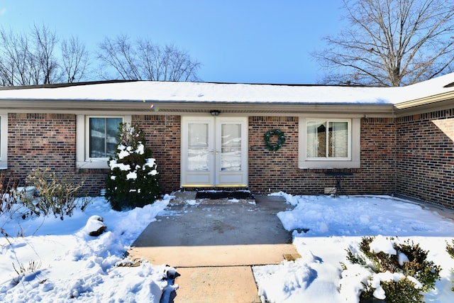 snow covered property entrance with french doors