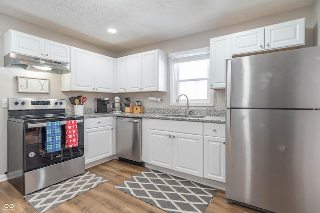 kitchen with light stone countertops, sink, stainless steel appliances, a textured ceiling, and white cabinets