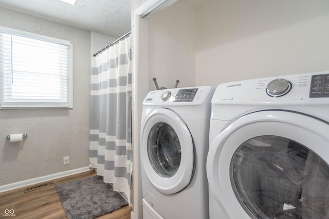 clothes washing area featuring hardwood / wood-style flooring and washing machine and clothes dryer