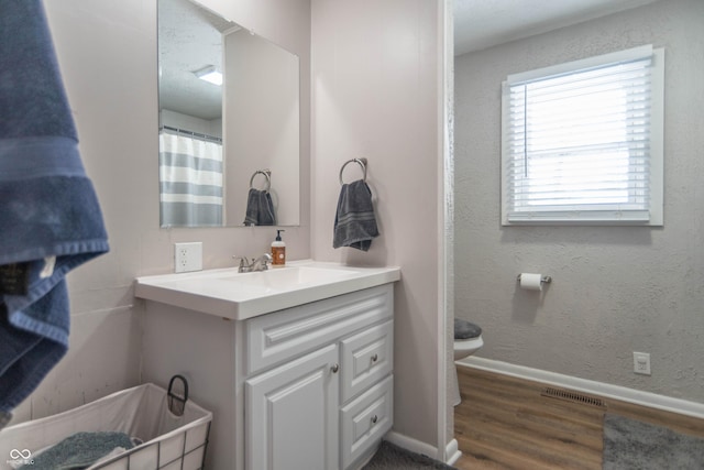 bathroom with hardwood / wood-style floors, vanity, and toilet