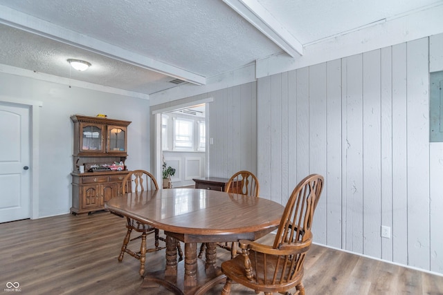 dining area featuring wood walls, beamed ceiling, a textured ceiling, and hardwood / wood-style flooring