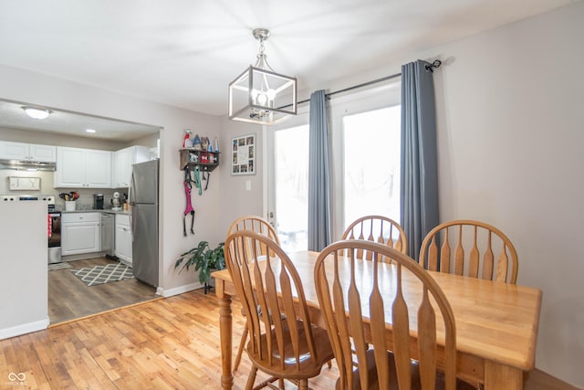 dining room with light wood-type flooring and a notable chandelier