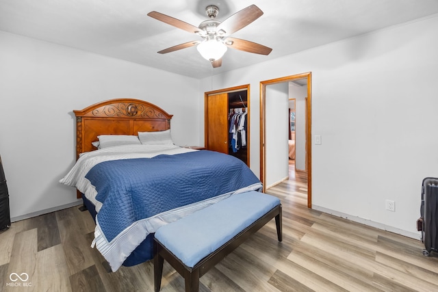 bedroom featuring a walk in closet, ceiling fan, a closet, and light hardwood / wood-style flooring