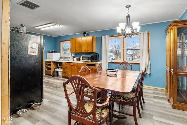 dining area featuring a notable chandelier, light hardwood / wood-style floors, ornamental molding, and a wealth of natural light