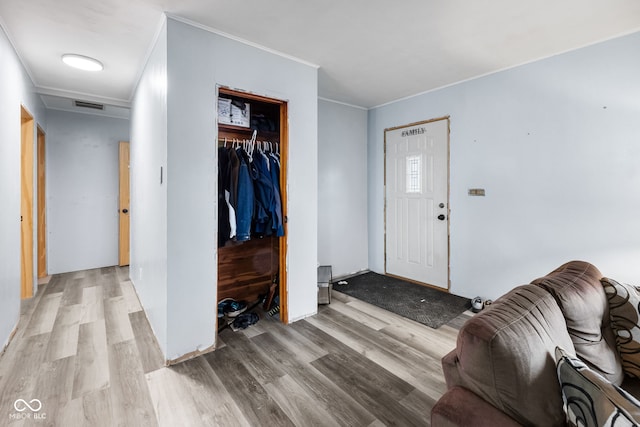 foyer entrance with crown molding and light hardwood / wood-style flooring