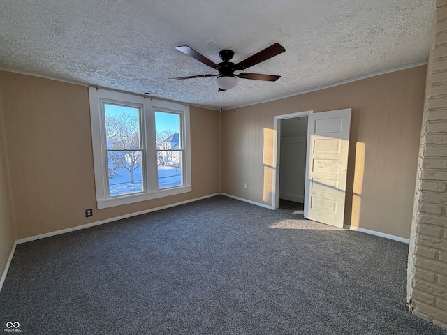 unfurnished bedroom featuring a textured ceiling, ceiling fan, crown molding, and dark carpet