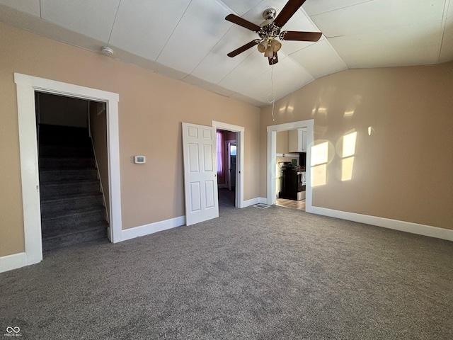 unfurnished bedroom with ensuite bathroom, vaulted ceiling, ceiling fan, dark colored carpet, and a walk in closet