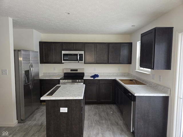 kitchen featuring sink, appliances with stainless steel finishes, dark brown cabinets, a kitchen island, and dark hardwood / wood-style flooring