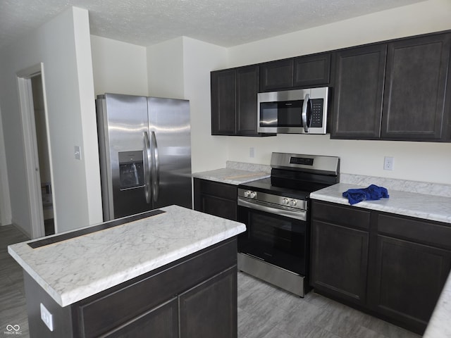 kitchen with a textured ceiling, a center island, and stainless steel appliances