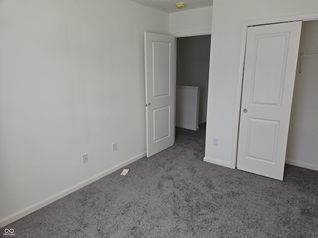 unfurnished bedroom featuring dark colored carpet and a closet