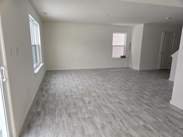 unfurnished living room featuring light hardwood / wood-style floors and a textured ceiling