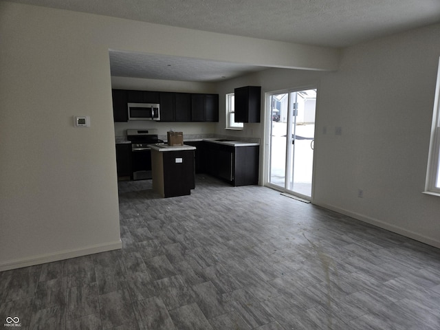 kitchen with dark hardwood / wood-style flooring, a kitchen island, a textured ceiling, and appliances with stainless steel finishes