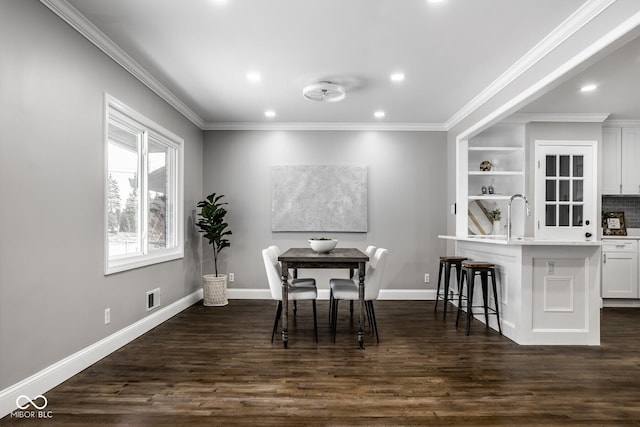 dining space with sink, dark wood-type flooring, and ornamental molding