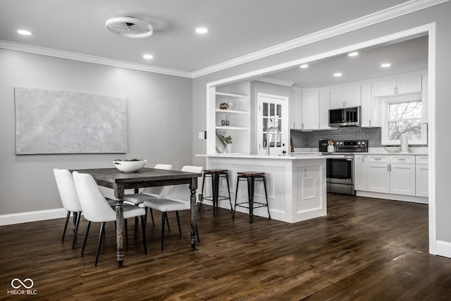 dining space featuring dark wood-type flooring, ornamental molding, and built in shelves