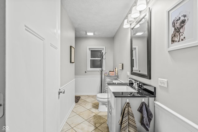 bathroom featuring tile patterned floors, vanity, toilet, and a textured ceiling