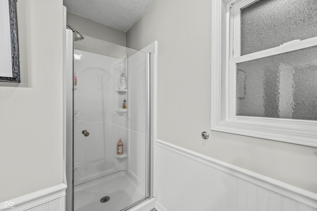 bathroom featuring a shower with shower door and a textured ceiling