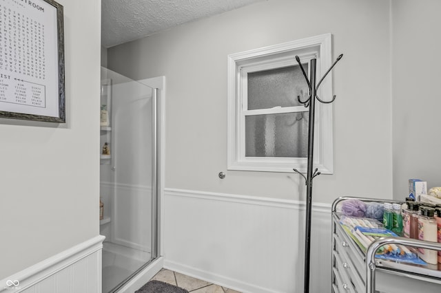 bathroom with a textured ceiling, tile patterned floors, and walk in shower