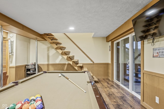 recreation room featuring wood-type flooring, a textured ceiling, wooden walls, and pool table