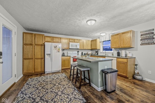 kitchen with a center island, white appliances, dark wood-type flooring, sink, and a breakfast bar area