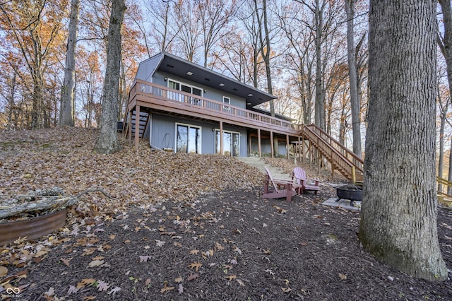 back of property with a wooden deck and a fire pit