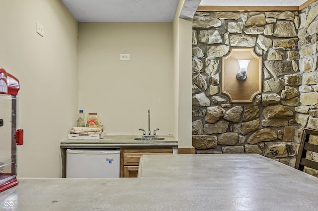 bar featuring a textured ceiling, white dishwasher, and sink