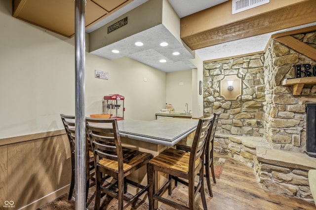 dining area with hardwood / wood-style floors, indoor wet bar, and wooden walls