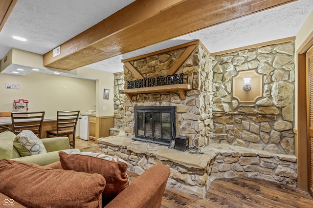 living room featuring a stone fireplace, wooden walls, hardwood / wood-style floors, and a textured ceiling