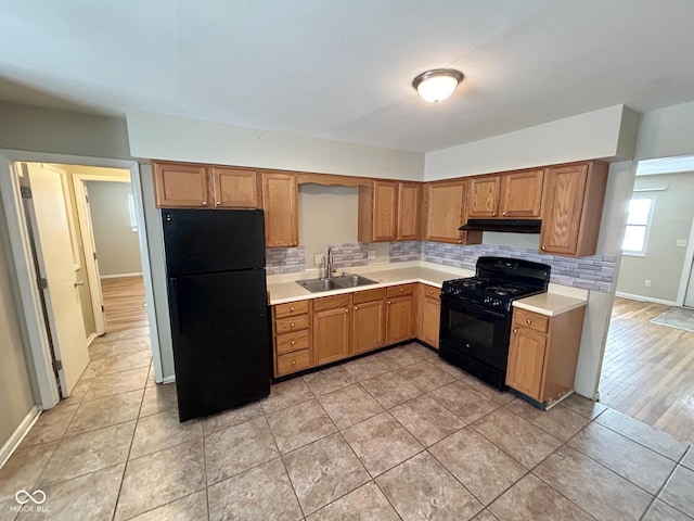 kitchen featuring black appliances, decorative backsplash, light tile patterned floors, and sink