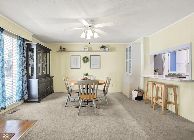 dining room featuring light carpet, ceiling fan, plenty of natural light, and a textured ceiling