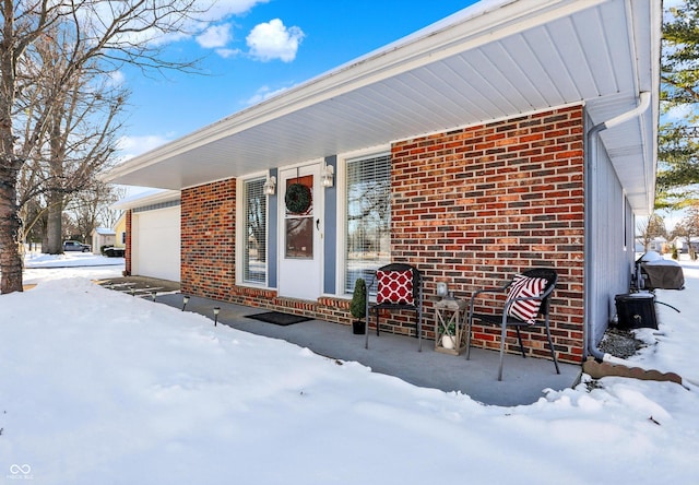 snow covered rear of property with a garage