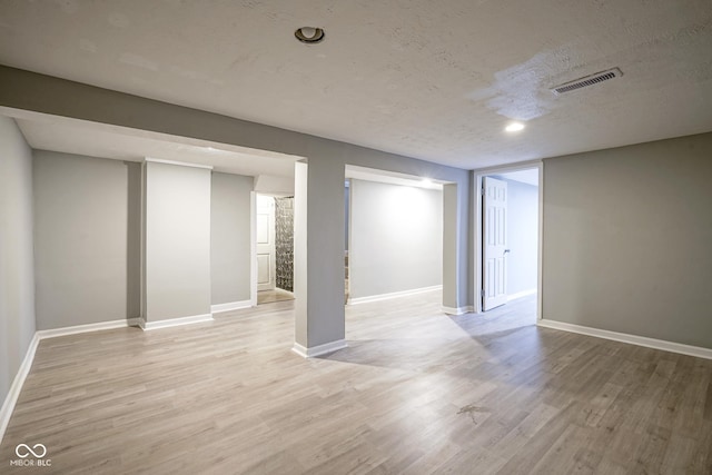 basement featuring light hardwood / wood-style floors and a textured ceiling