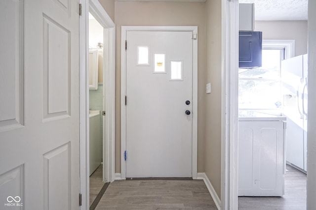 entryway with washer / clothes dryer and light wood-type flooring