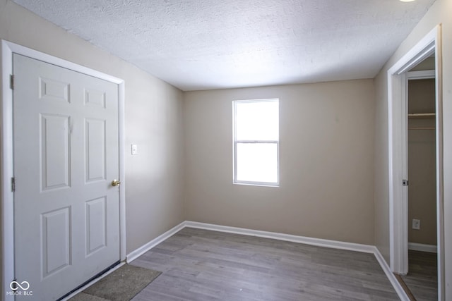 unfurnished bedroom featuring a textured ceiling, a closet, and light wood-type flooring