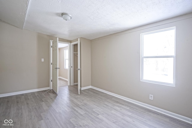 spare room with a textured ceiling and light hardwood / wood-style floors